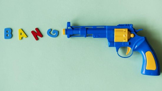 Criança dentro da caixa brincando com arma de brinquedo  - A produção e comercialização destas armas estão proibidas (foto: Reprodução/ Pexels)